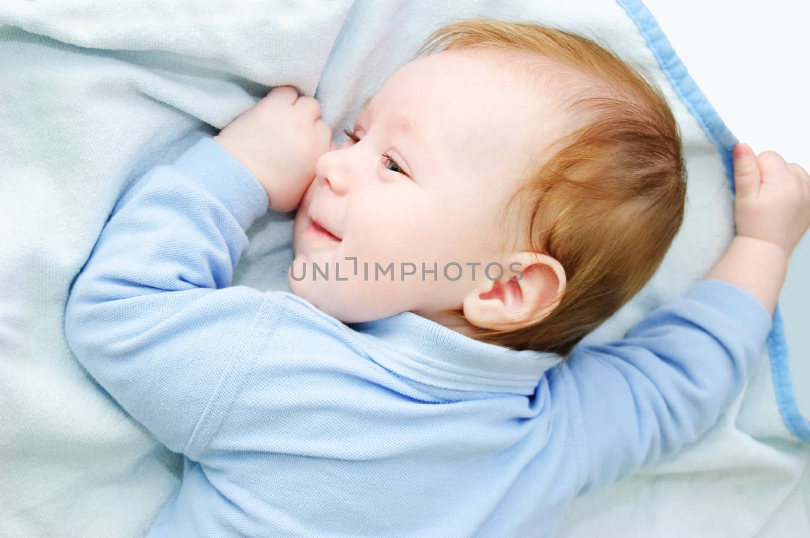 Blue eyed baby boy lying on blanket