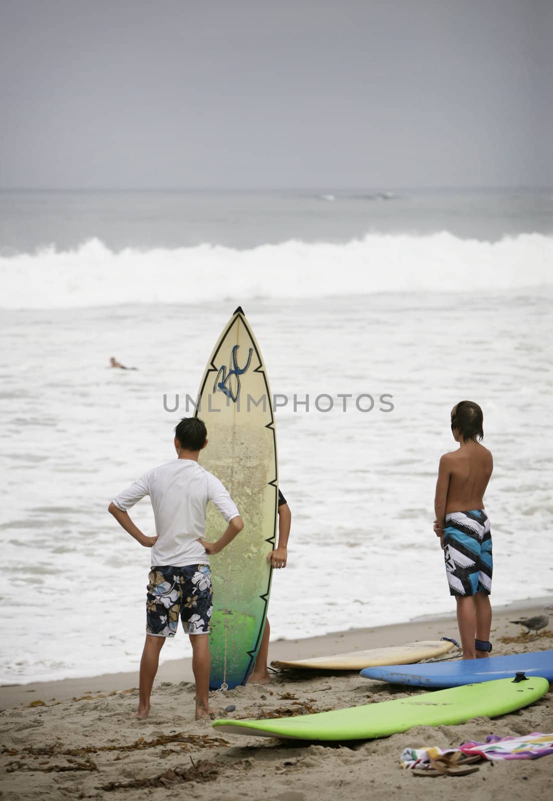 young surfers standing on beach watching the surf