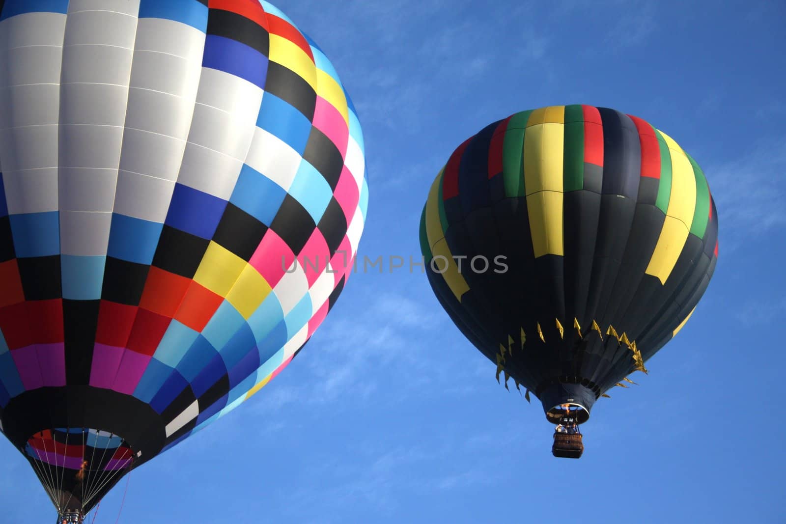 Pair of hot air balloons flying accross a blue sky