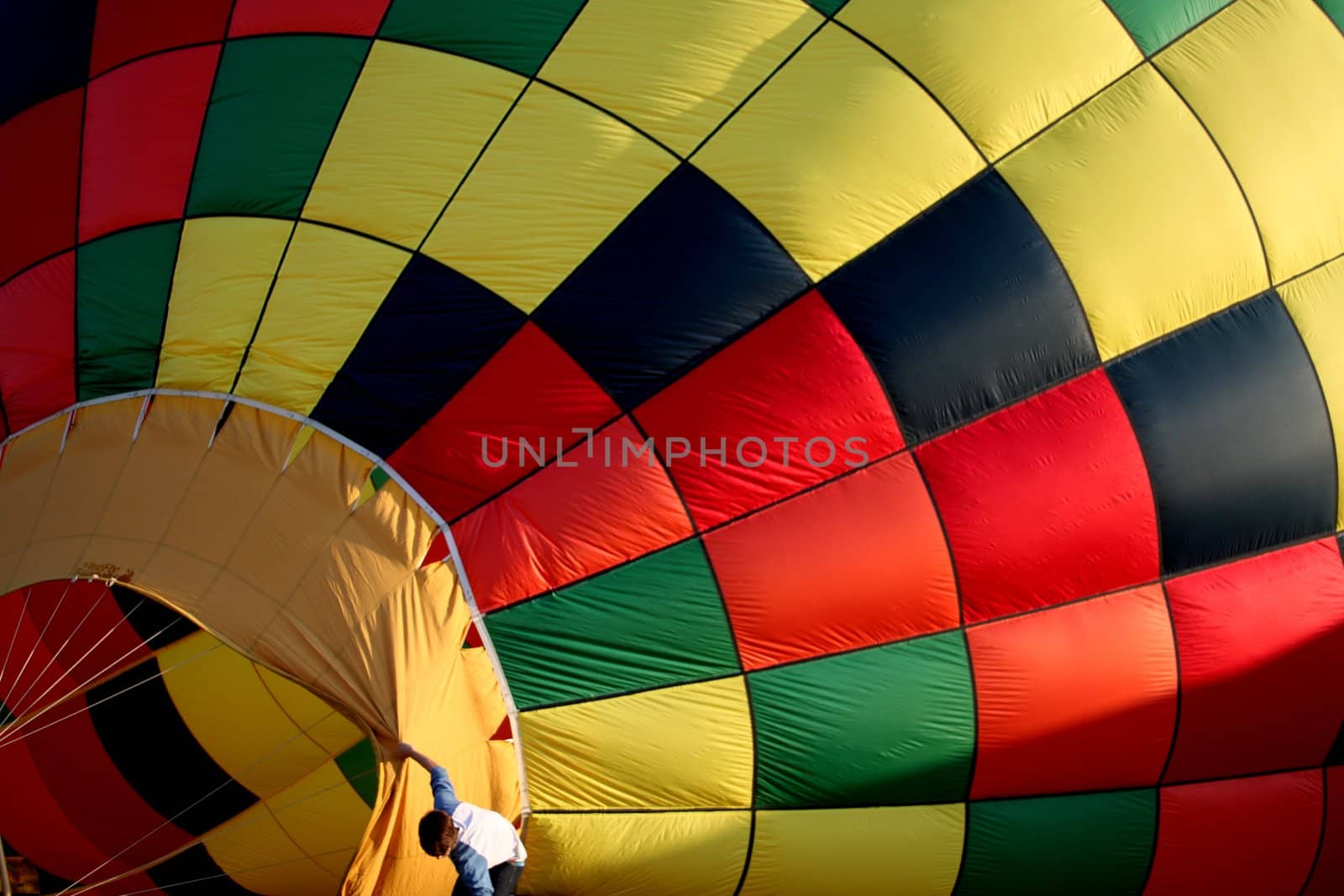 Young boy holding open a hot air balloon taking on some air