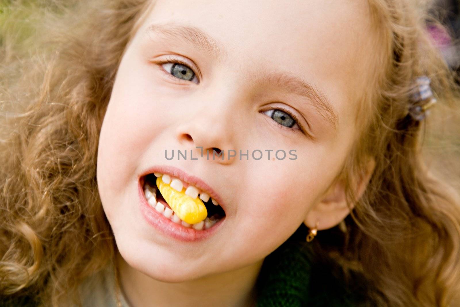 Portrait of the cheerful little girl with a candy 