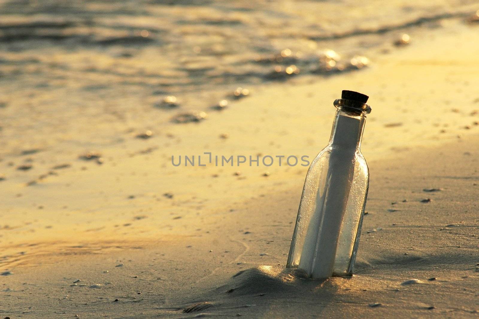 Dramatic late day sunlight highlights a message bottle that washed ashore. Can be used for many themes including help, help desk, customer service themes and more.