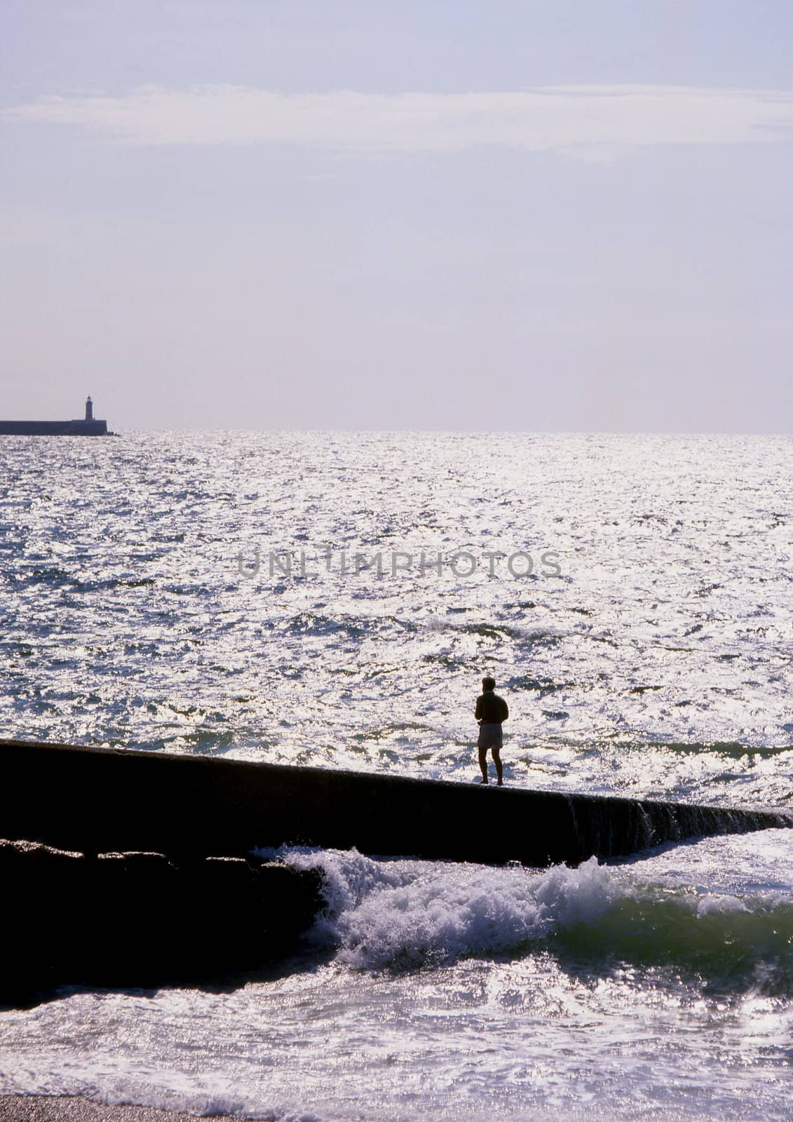 Man standing on seaside breakwater during rough seas