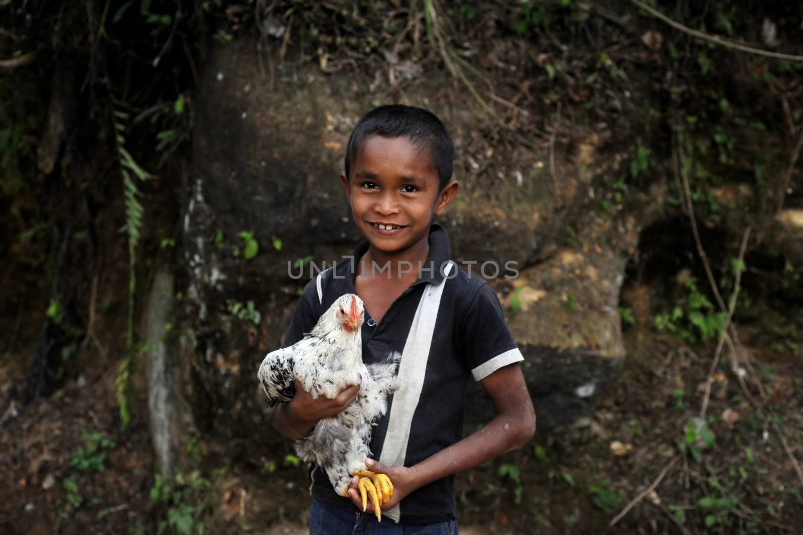 Neluwa, Sri Lanka - January 27, 2011: Sri Lankan boy from small sri lankan village carrying  chicken in his hands and looking to the camera