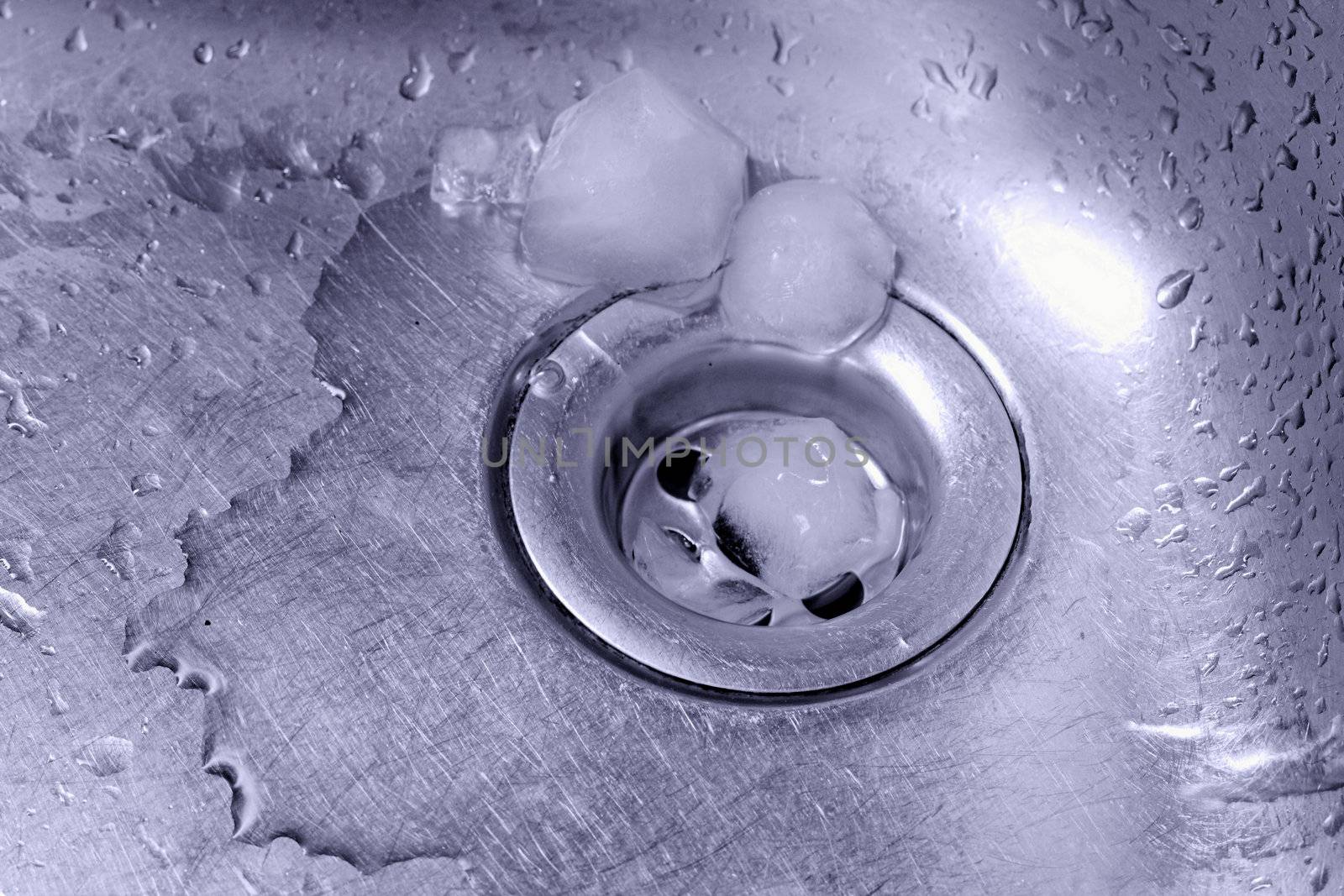 Metallic Kitchen sink with melting ice and water drops in blue duotone shot from low angle