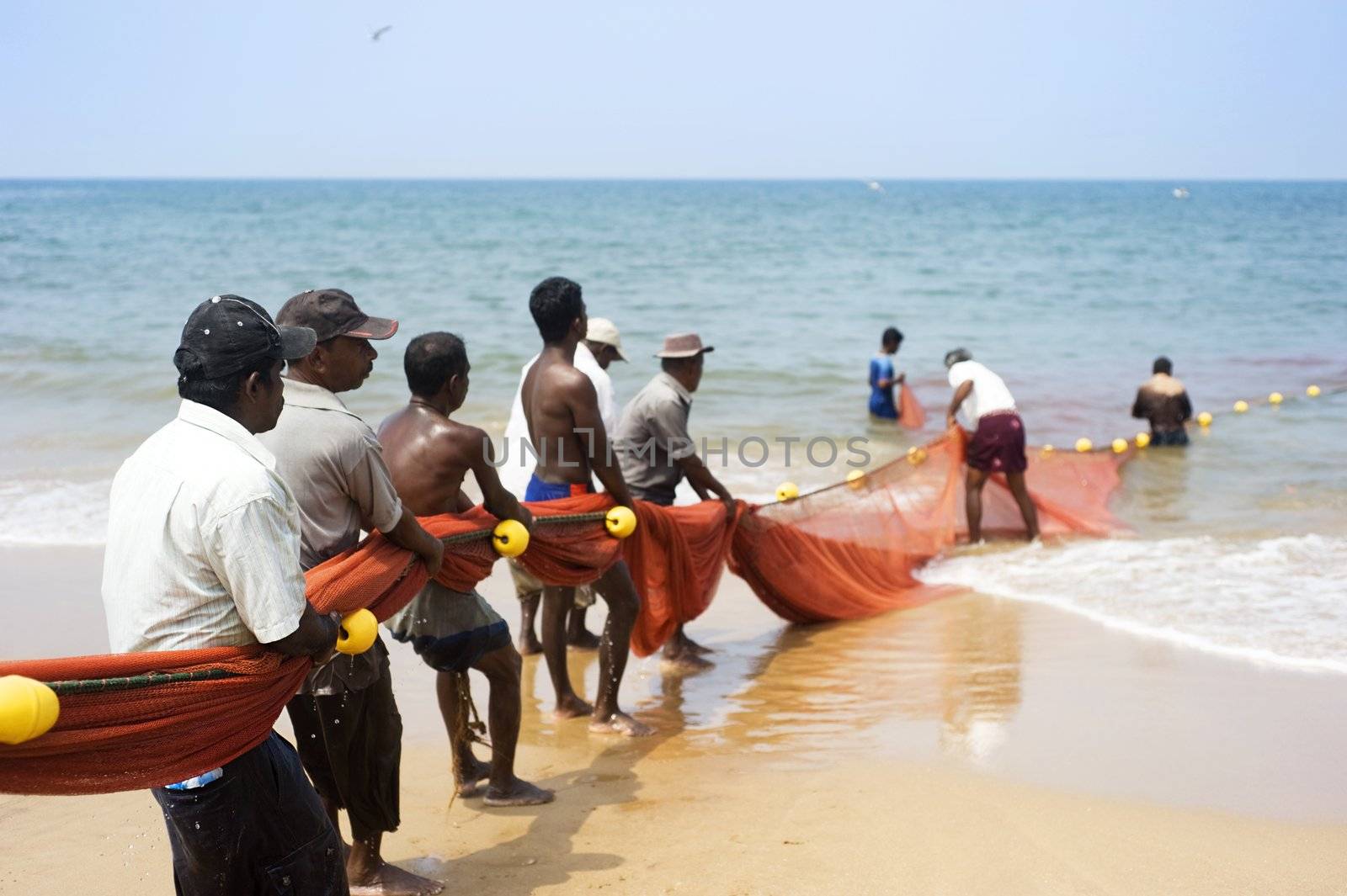 Hikkaduwa, Sri Lanka - Feb 19, 2011: Local fishermans pulling net from the ocean. Fishing in Sri Lanka is a tough job but this is the way they earn their living