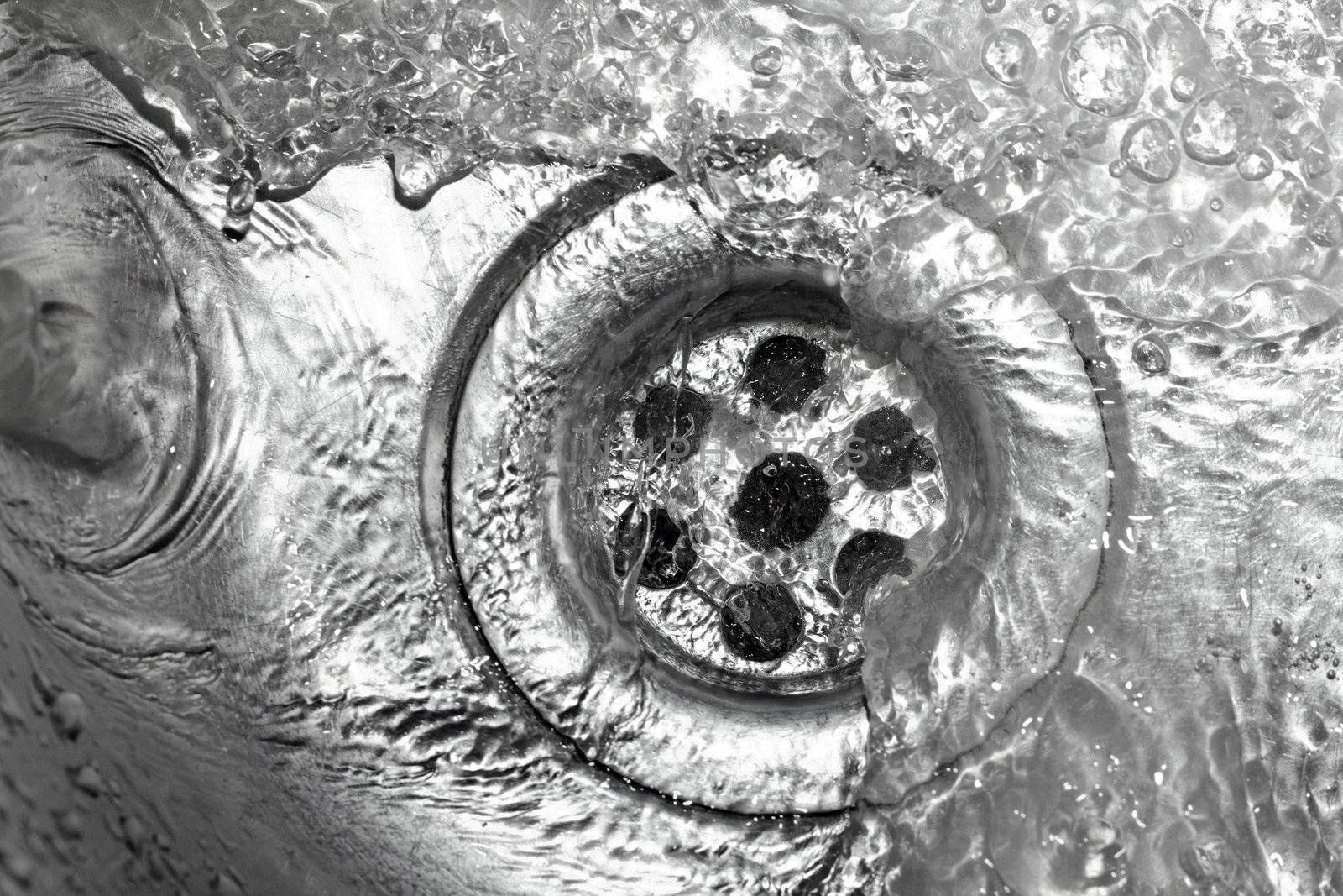 Metallic Kitchen sink swirly water flow and drops shot from above