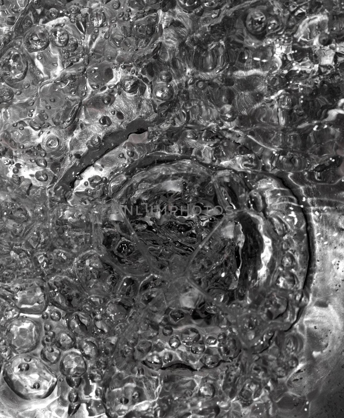 Metallic Kitchen sink water flow and drops shot from above, abstract -useful as background