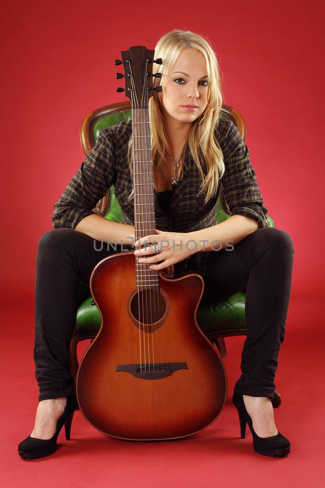 Photo of a young blond female holding a acoustic guitar.