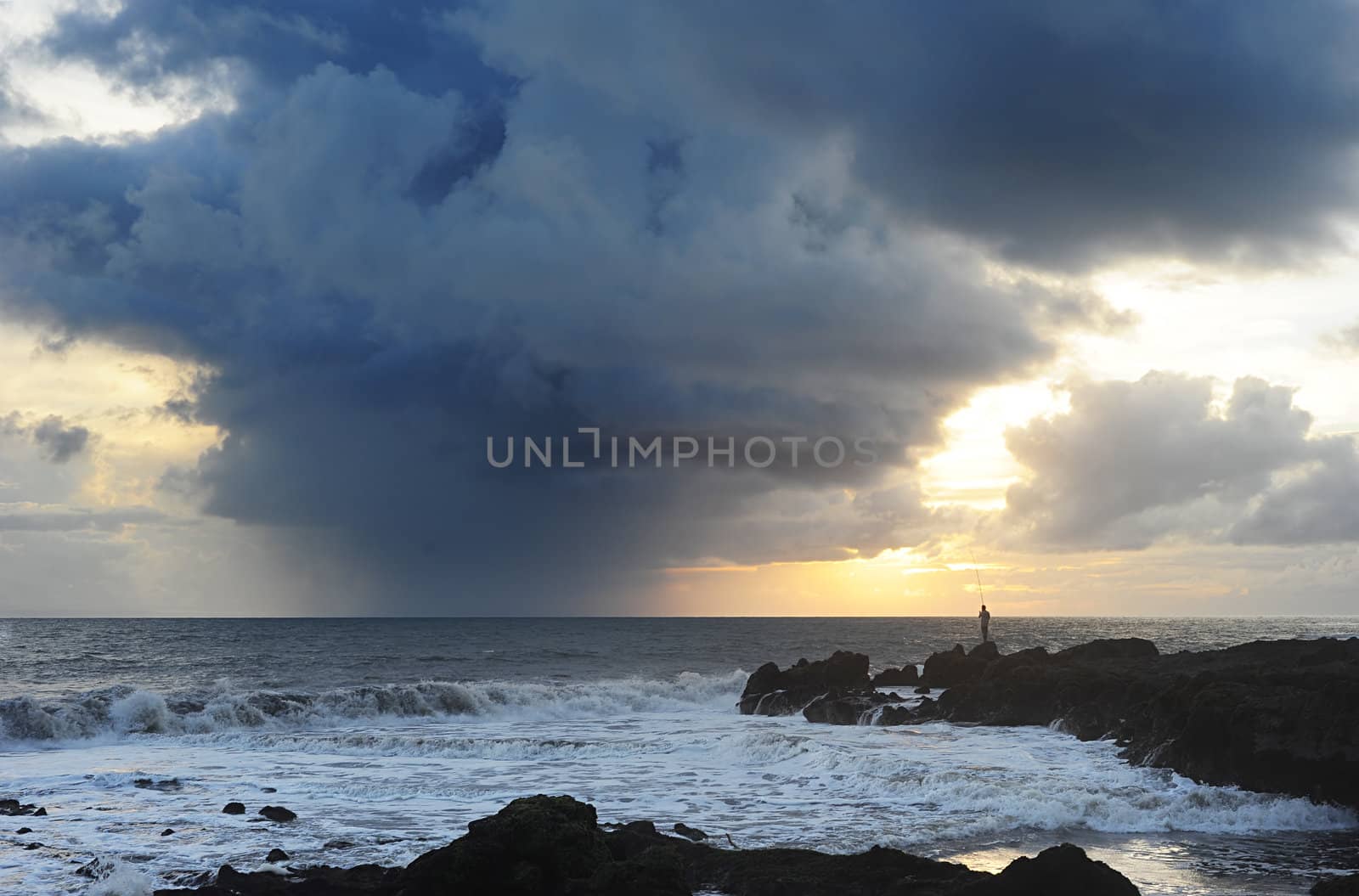 Fisherman fishing at sunset before storm