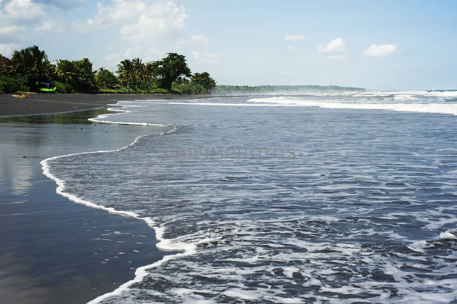 Tide coming in from the sea on black sand beach. Bali, Indonesia
