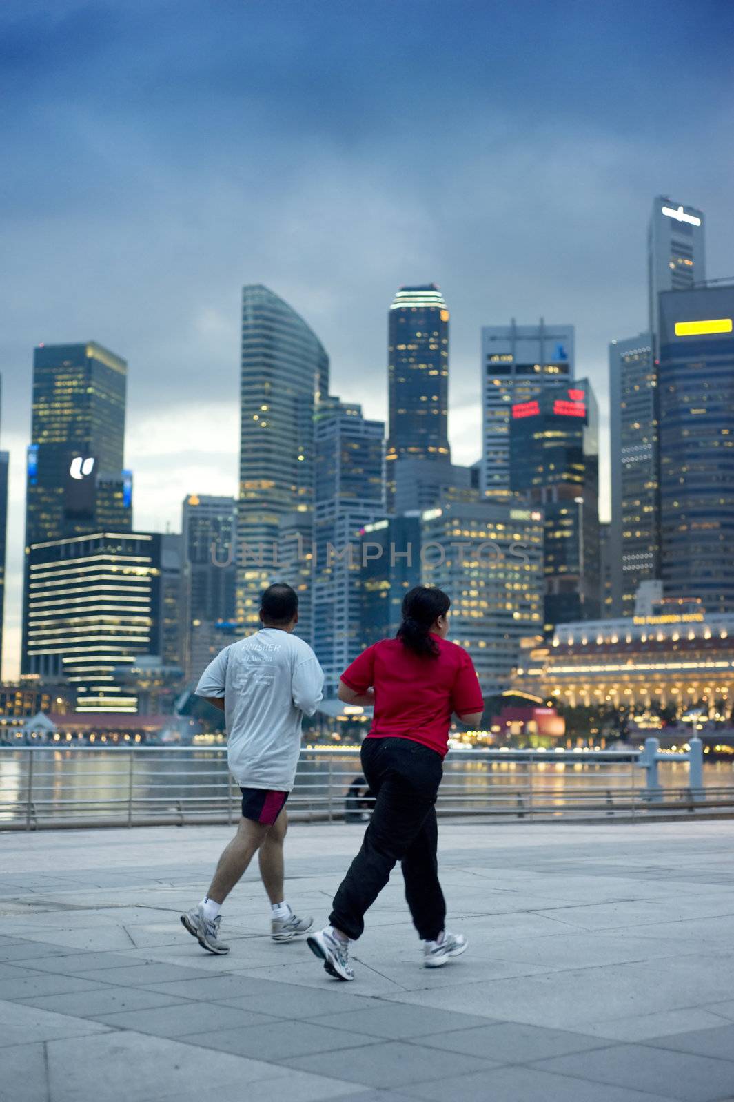 Singapore, Republic of Singapore - May 3, 2011: People running in the evening on embankment in front of business center. Running is very popular sports in Singapore