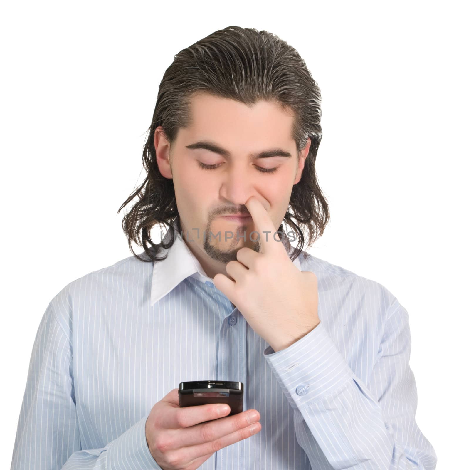 Young funny dark haired guy in light blue shirt dials on his mobile phone and picks his nose isolated on white