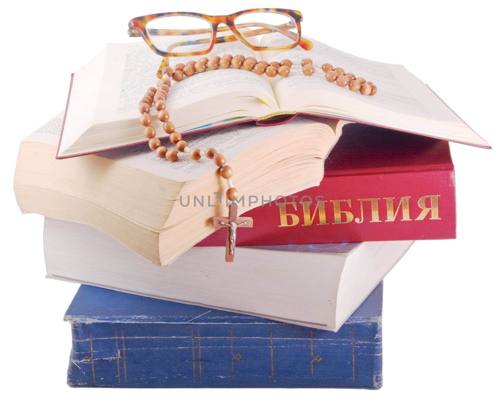 Open Holy Bible lying on stack of old books with glasses, cross and beads