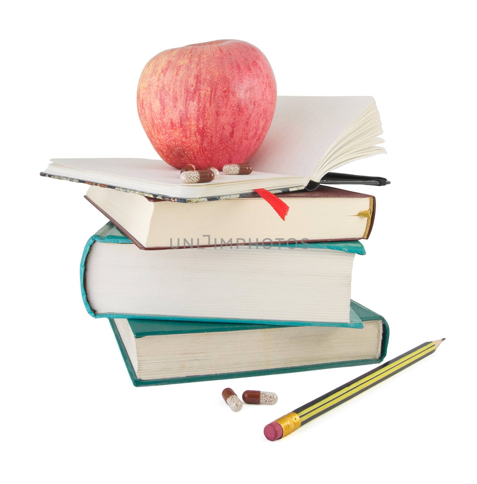 Pills and red apple on textbook pile as metaphor of efective learning