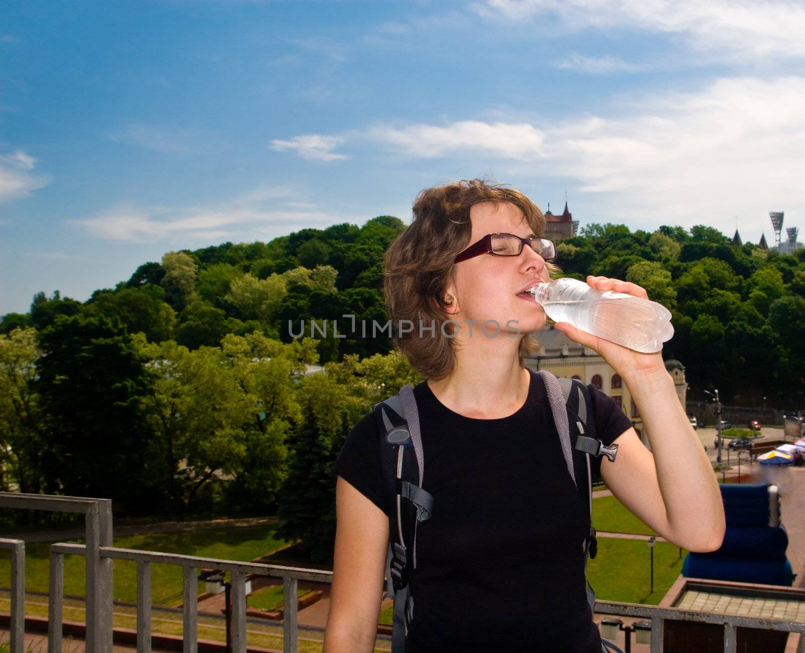 Young woman walking in the city and refreshing herself with cold fresh water