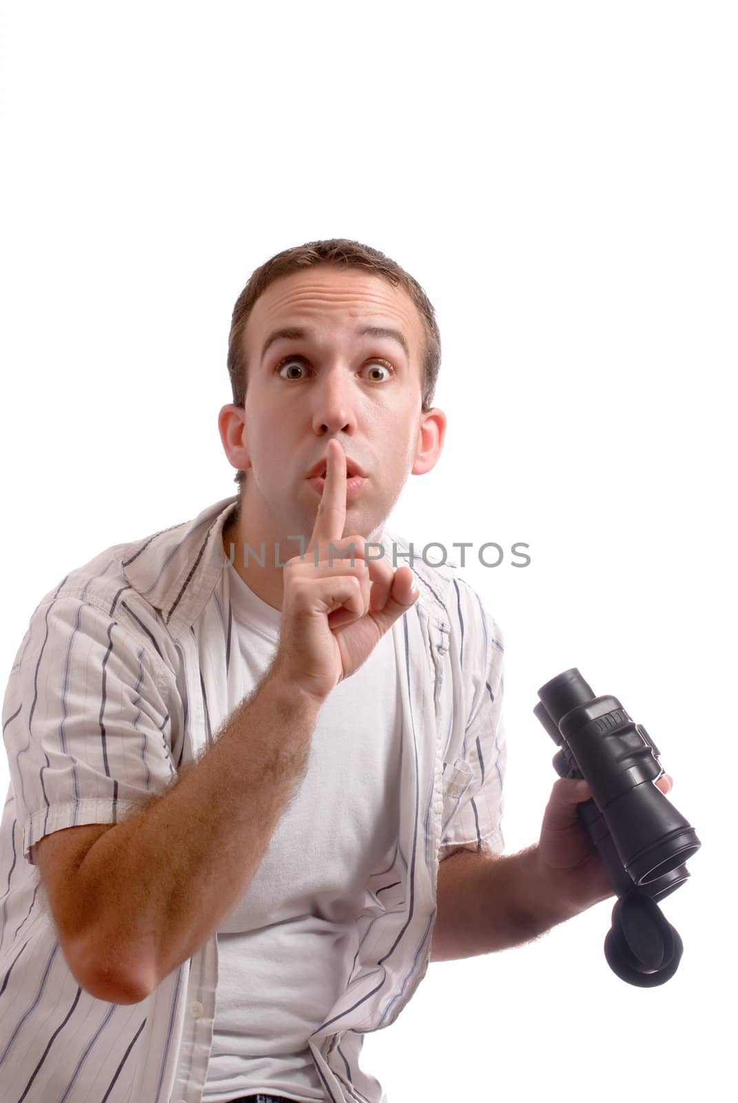 A young man is telling the viewer to be quiet while he holds his set of binoculars, isolated against a white background