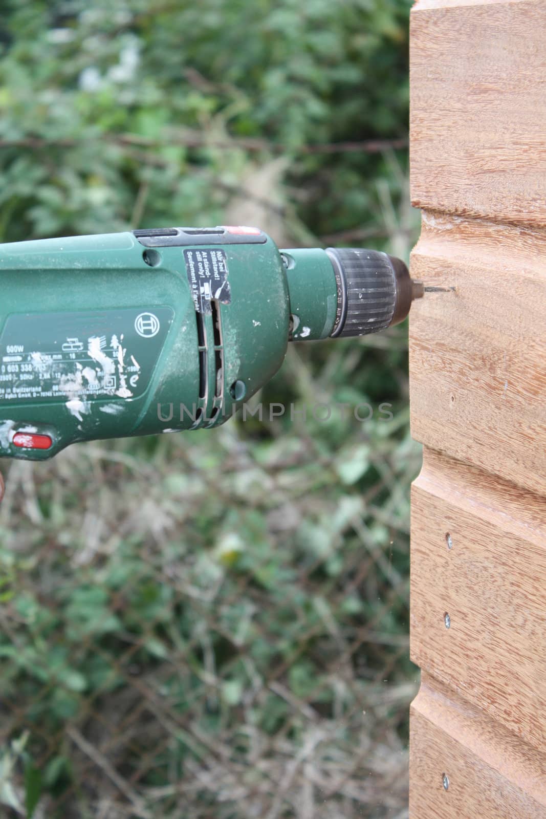 Working with a Power drill on a wooden construction by studioportosabbia