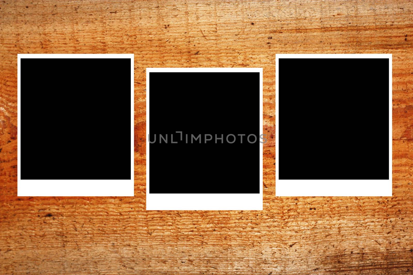 set of three old blank polaroids frames lying on a wood surface 