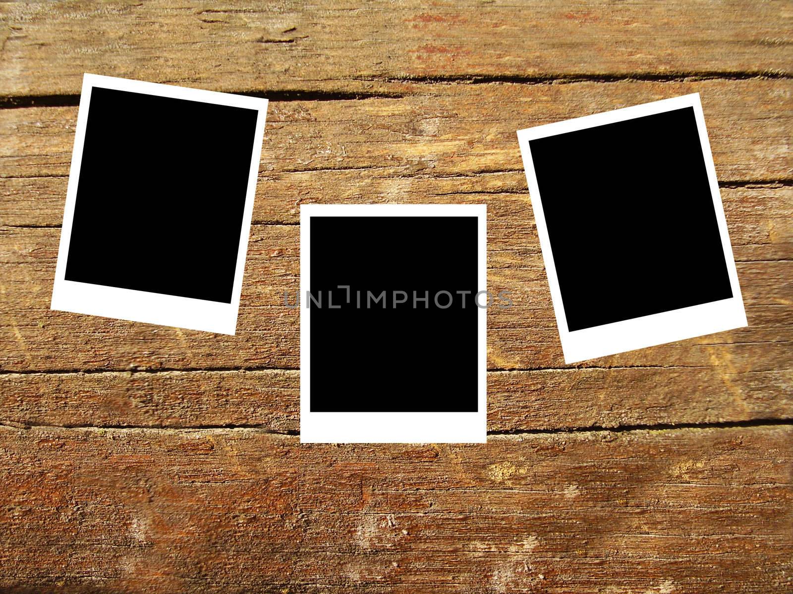 set of three old blank polaroids frames lying on a wood surface 
    