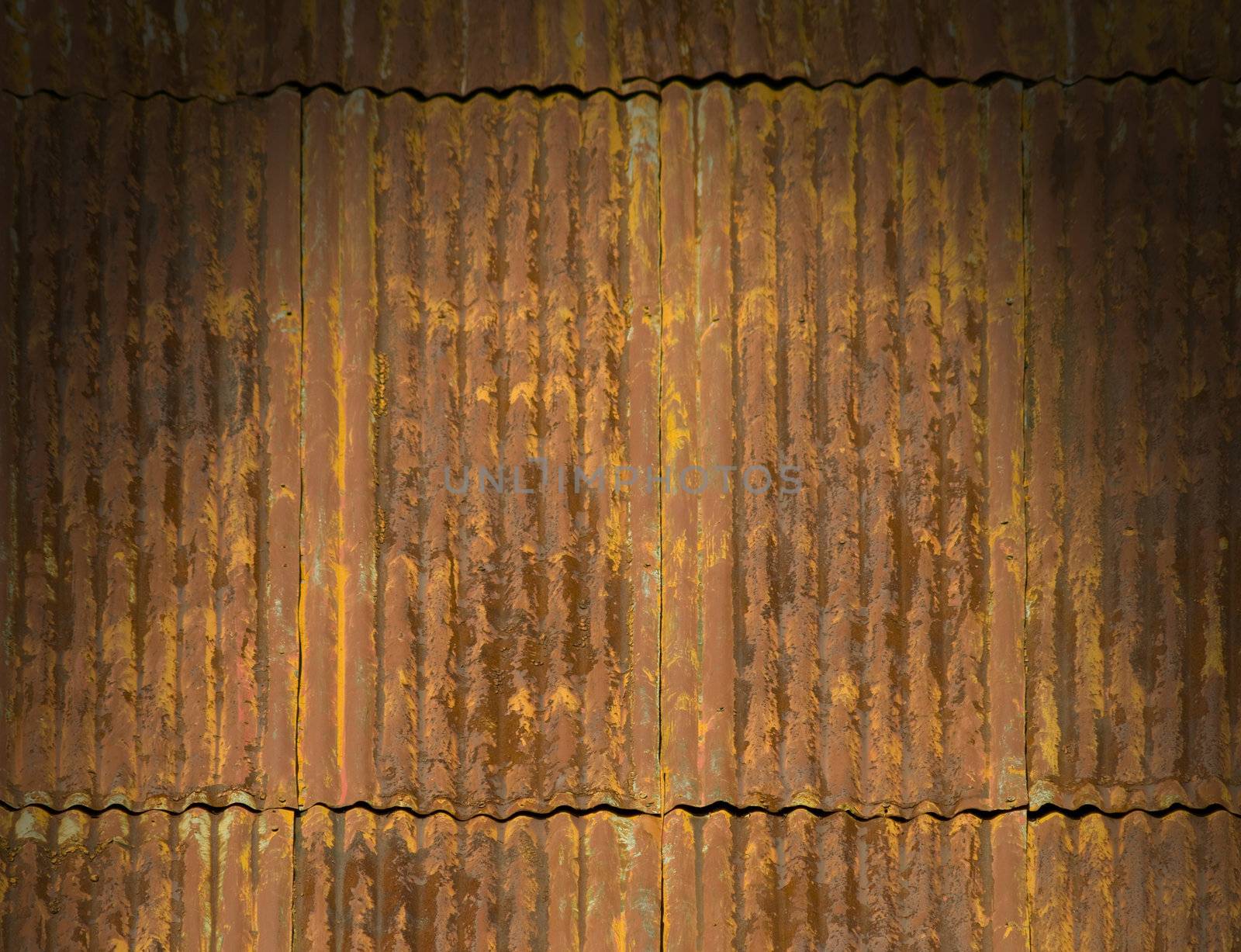 Corroded and rusty corrugated metal roof panels lit dramatically