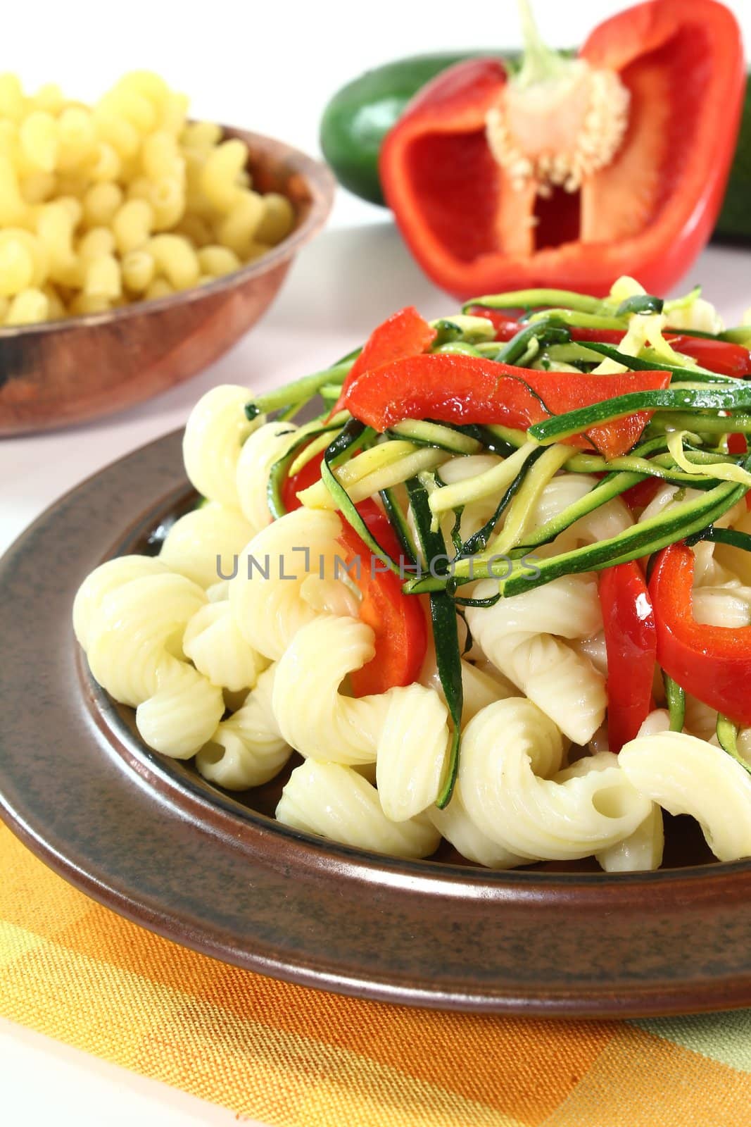 vegetarian pasta with zucchini and peppers on a white background