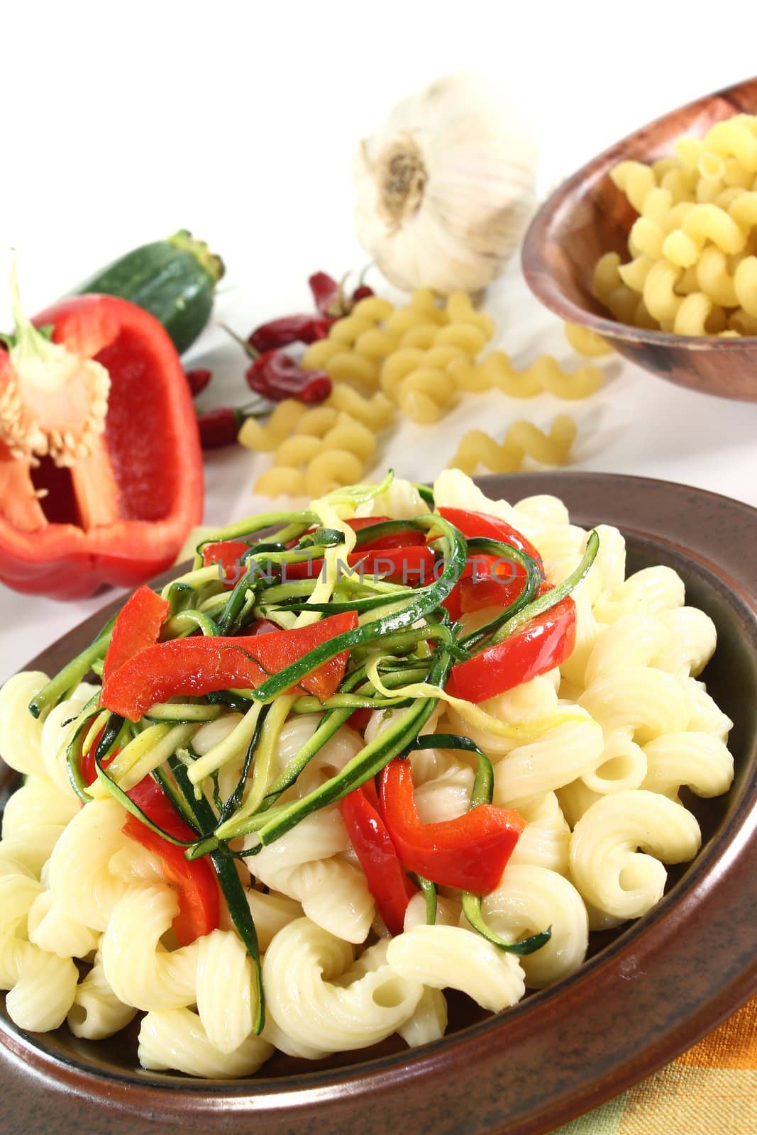 vegetarian pasta with zucchini and peppers on a white background