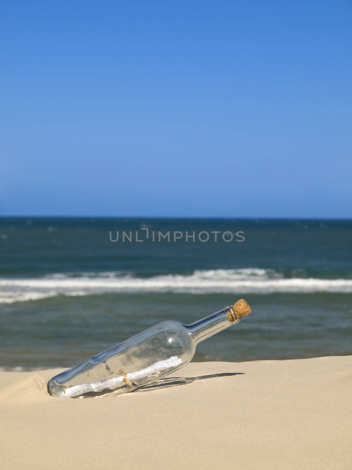 A bottle with a message inside is buried on the beach.