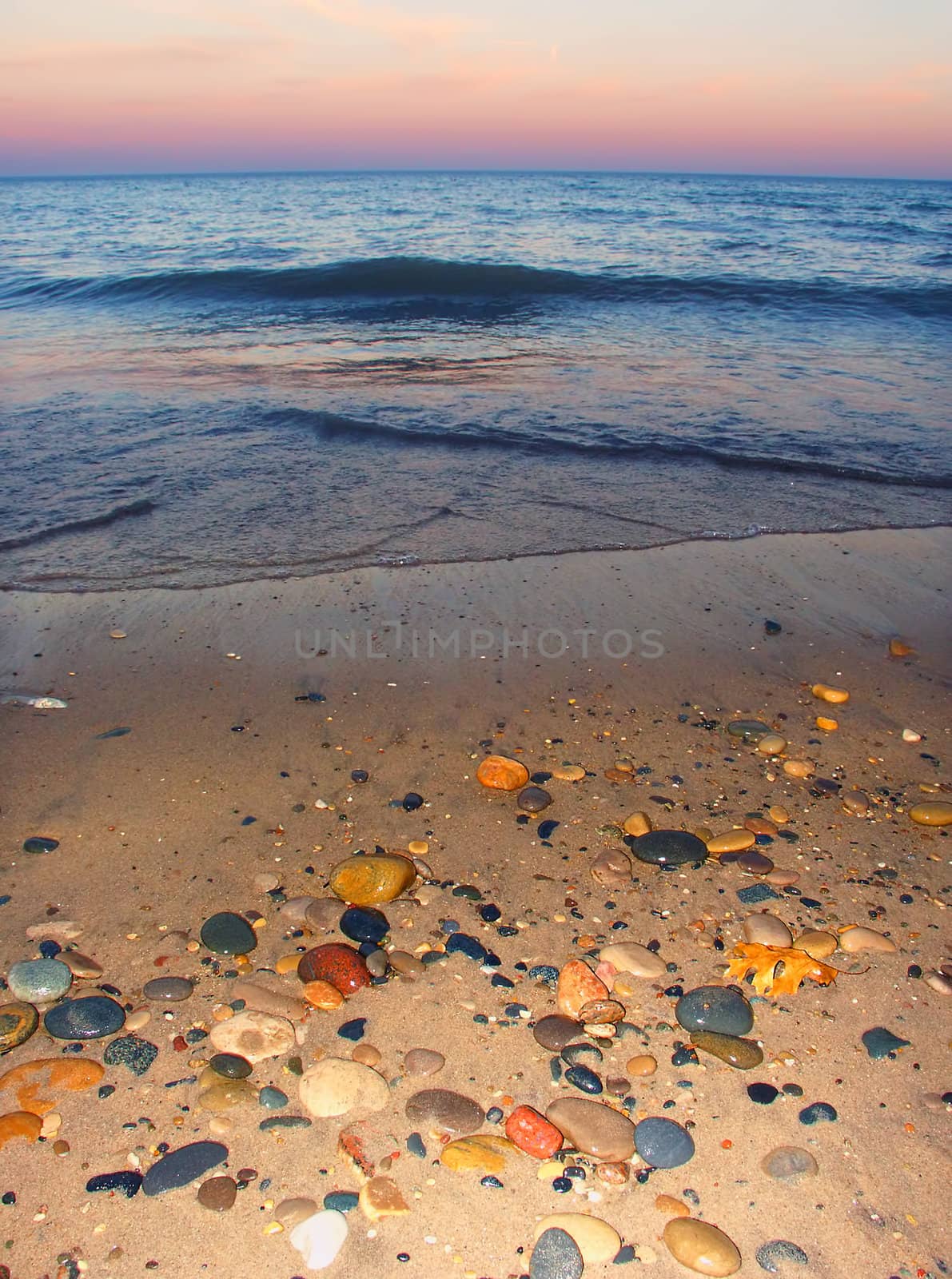 Smooth stones dot the sand at sunset over Lake Michigan at Illinois Beach State Park.