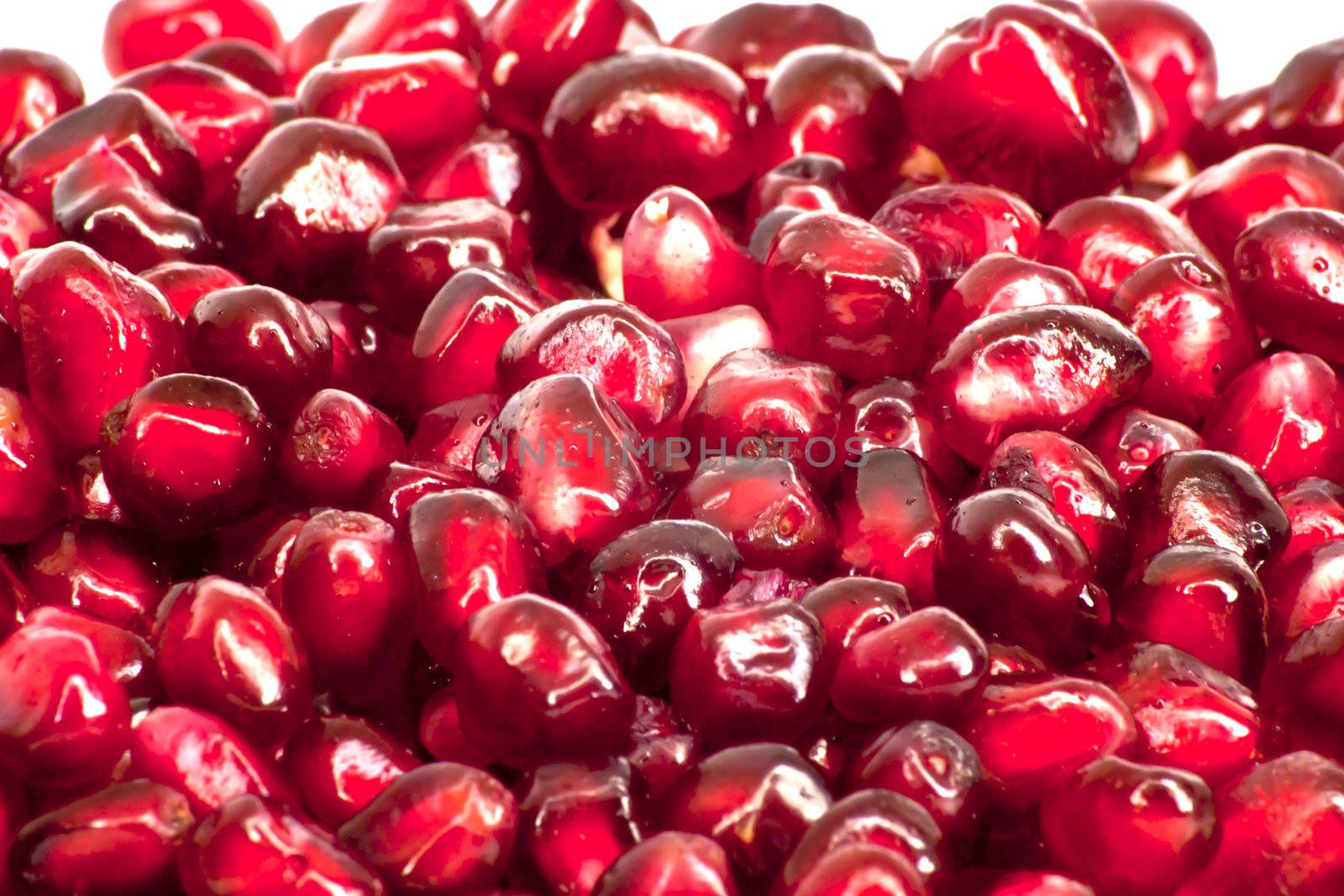 Extreme close up background of a red juicy ripe pomegranate fruit seeds 
