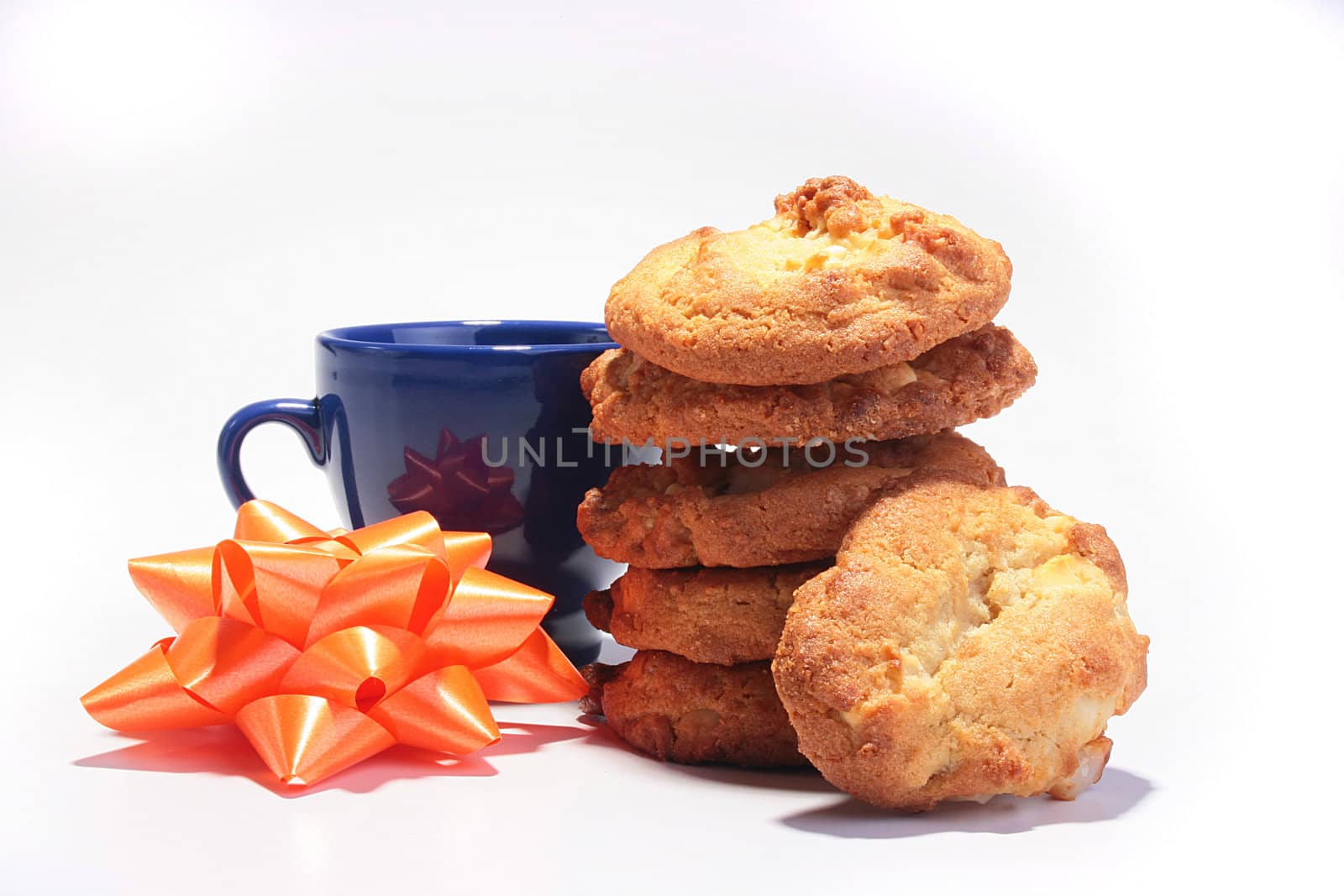 Sweet cookies against a dark blue cup for tea and a celebratory bow.