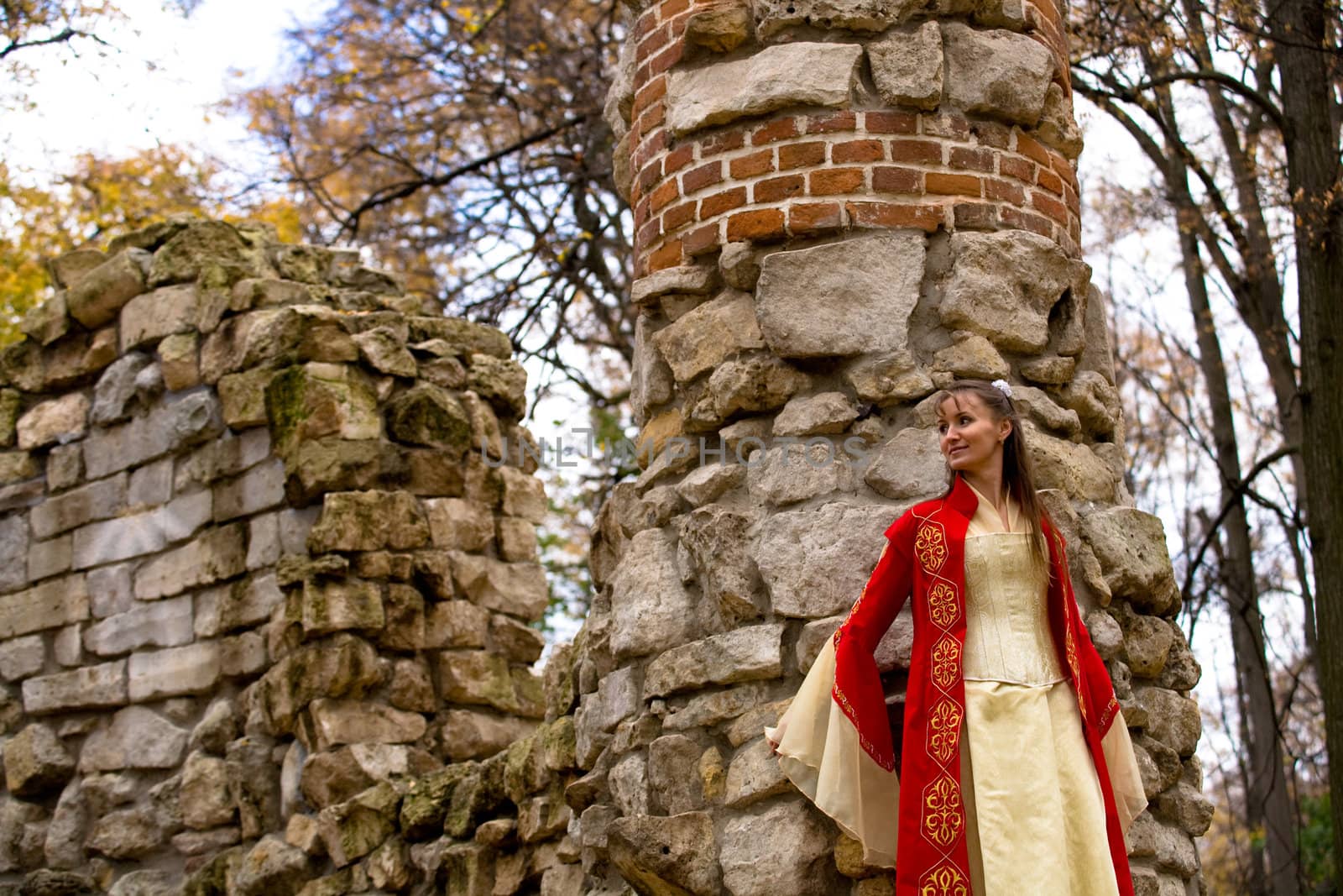 lady in medieval red dress standing near old wall
