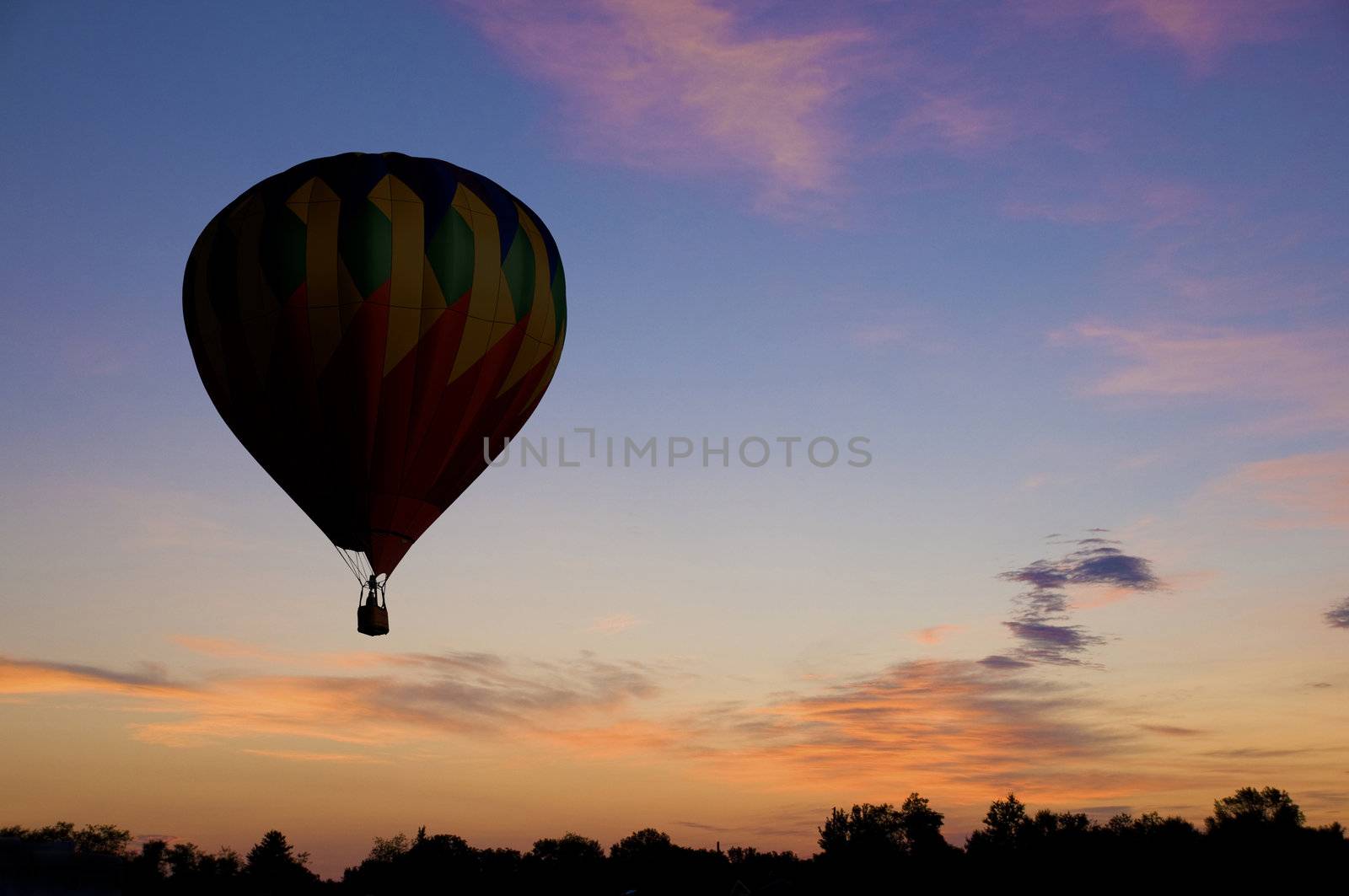 Hot-air balloon floating against a reddish dawn or dusk sky