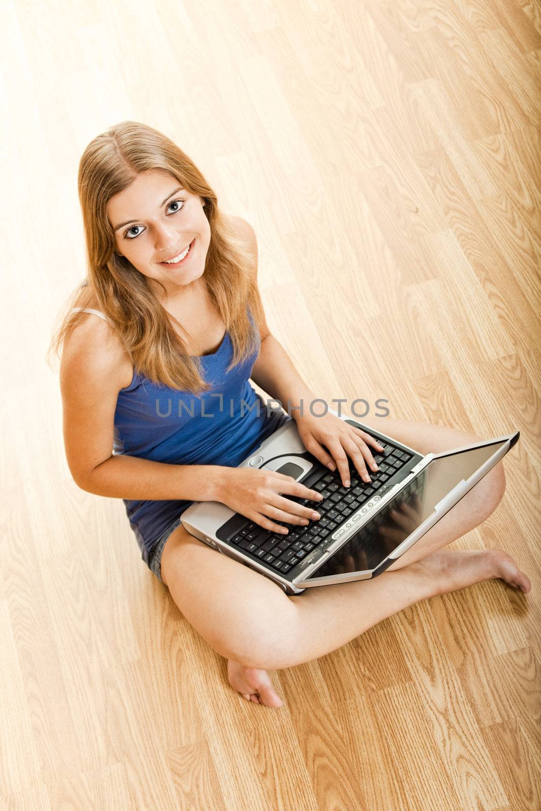 Beautiful young woman sitting on floor and working on a laptop