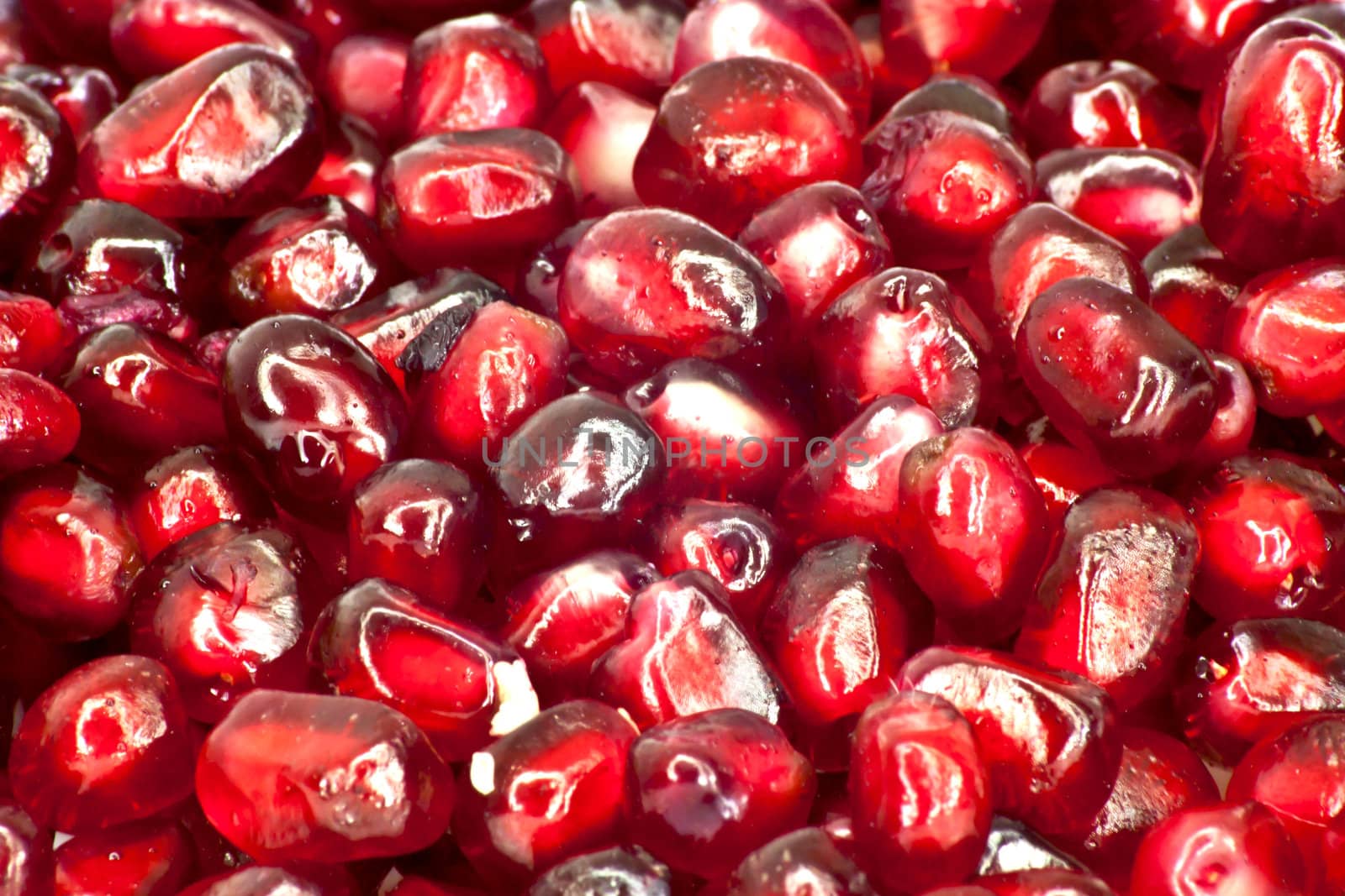 Extreme close up background of a red juicy ripe pomegranate fruit seeds 