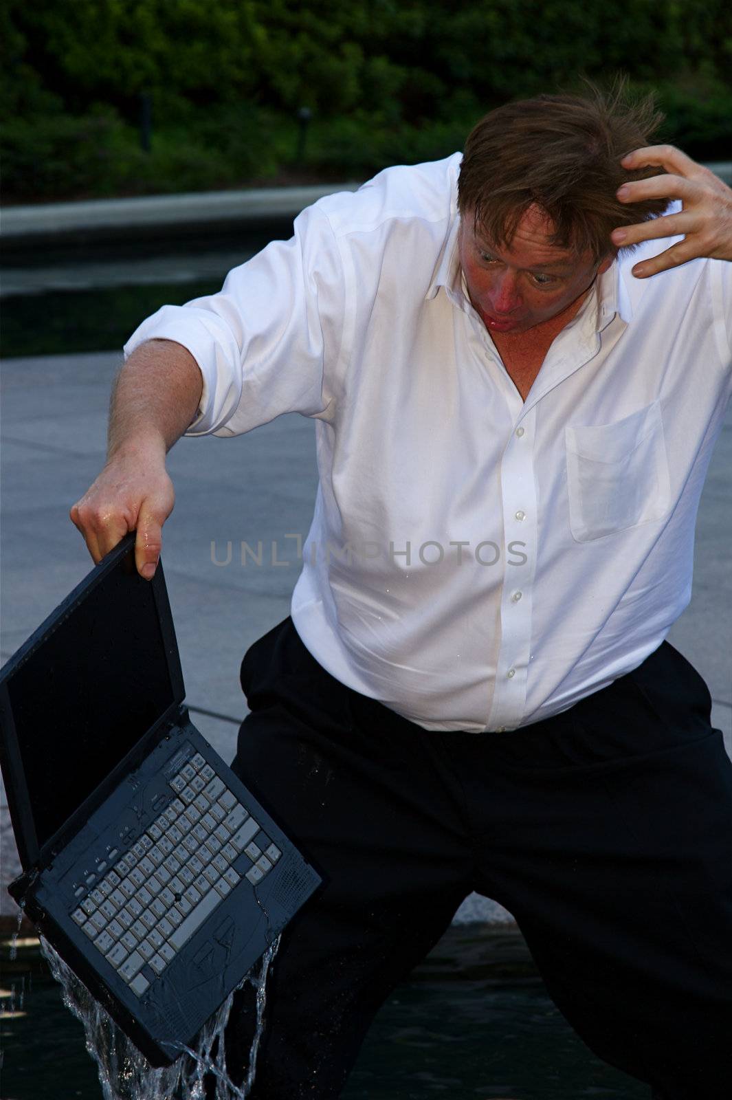 A laptop dropped into water by a businessman