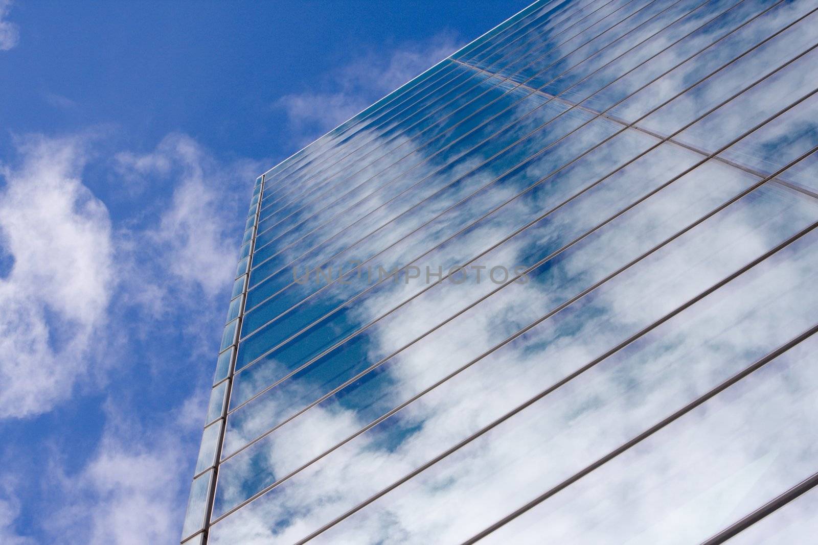 Modern glass office building reflecting the clouds.