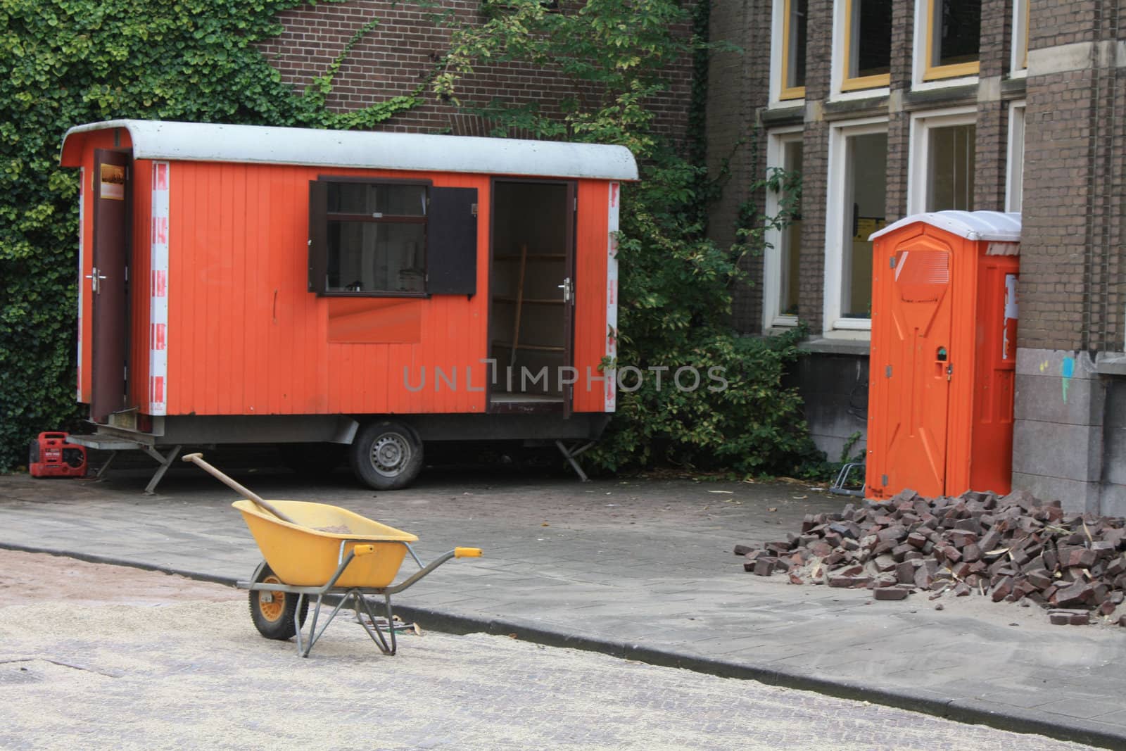 Shelter, toilet and wheelbarrow near a construction site