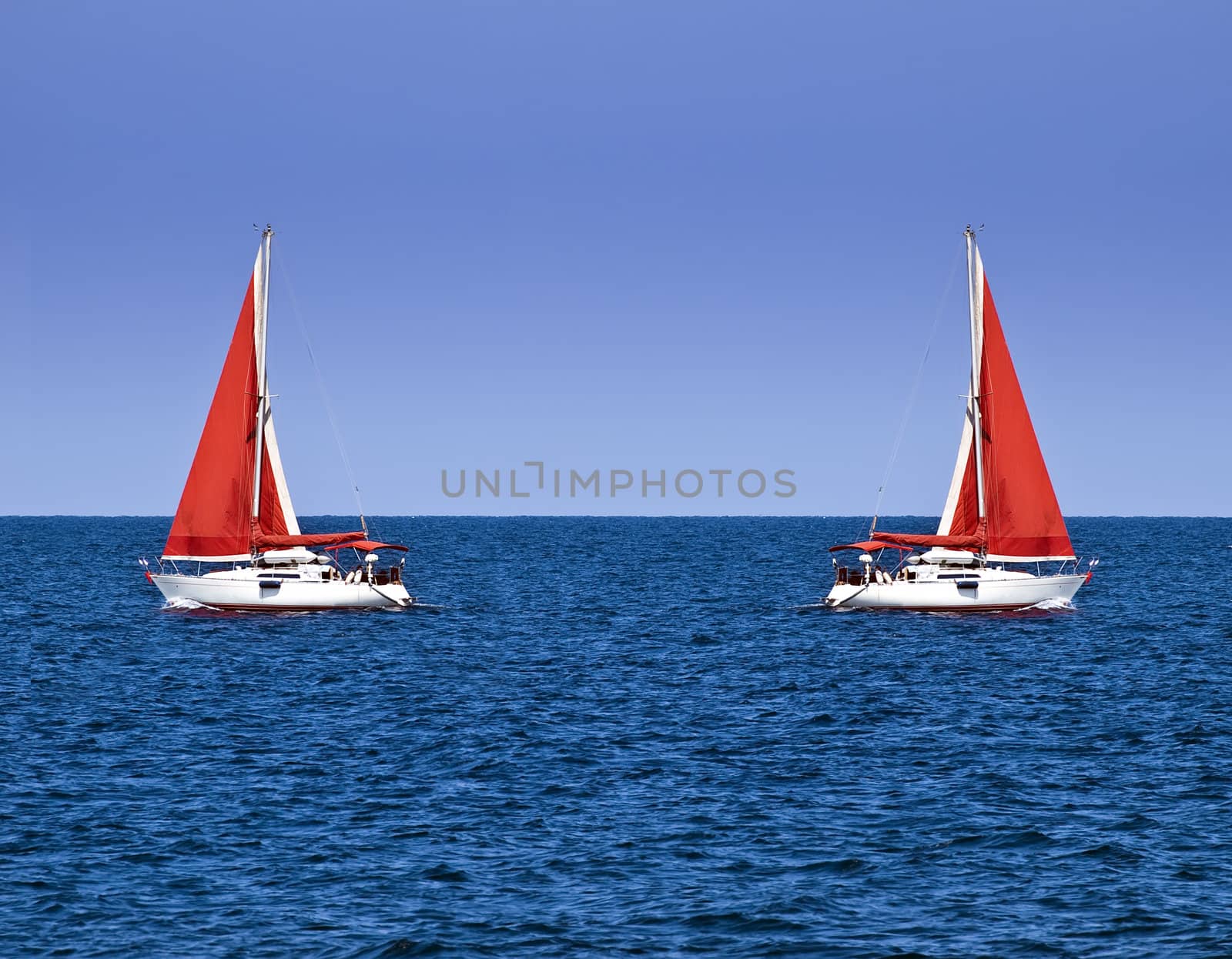 Yacht with a red sail offering crisp contrast against sky and ocean blue