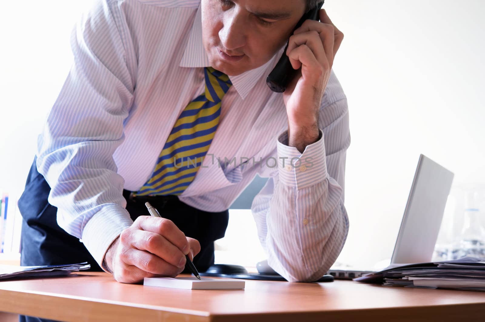 Closeup of a businessman talking on telephone and writing a note
