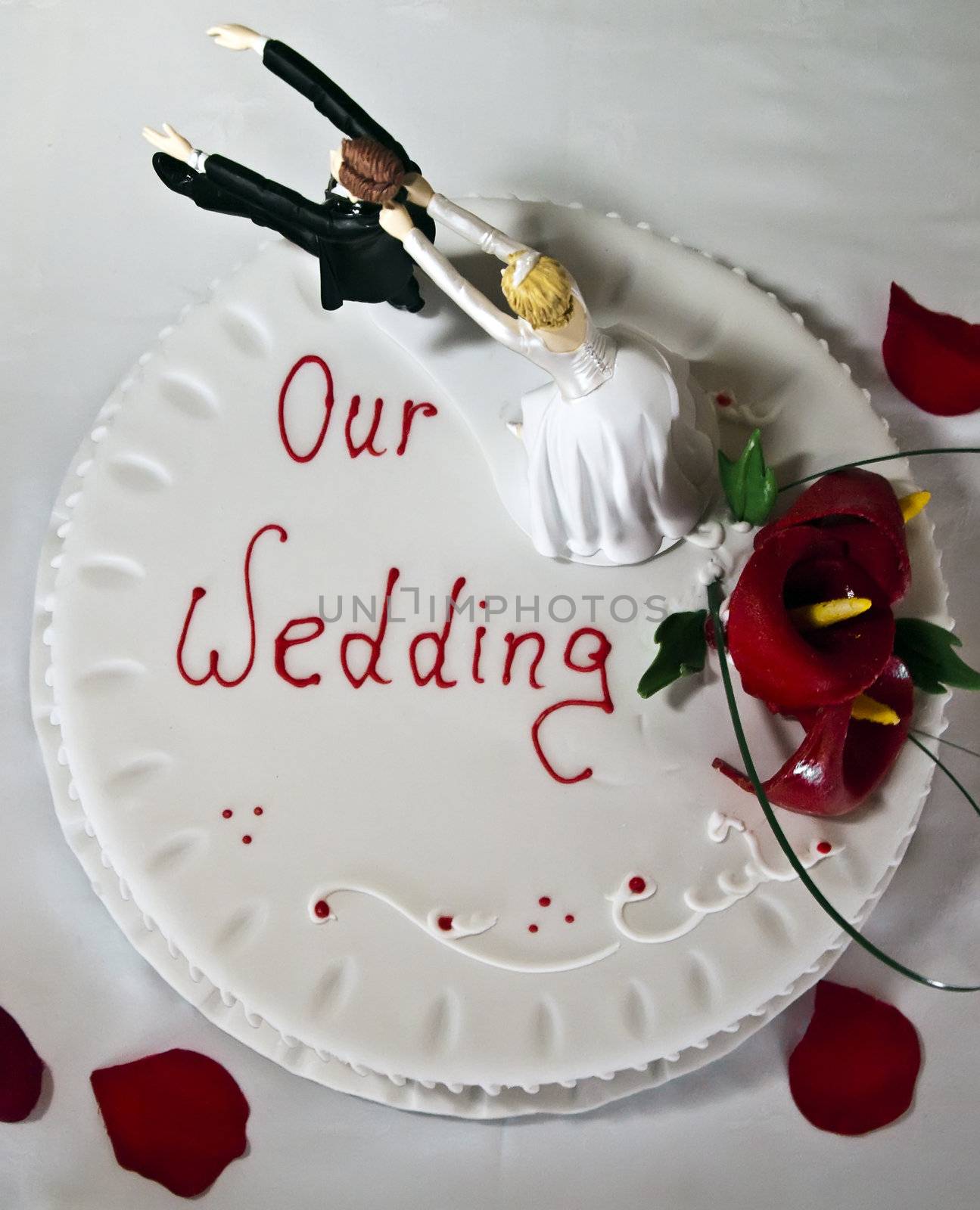 Wedding cake on a white backdrop with red rose petals