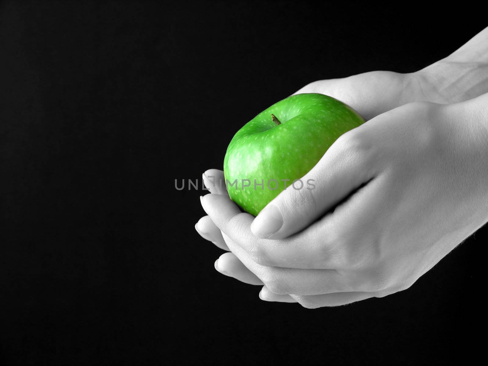 Green Apple in hands on black background