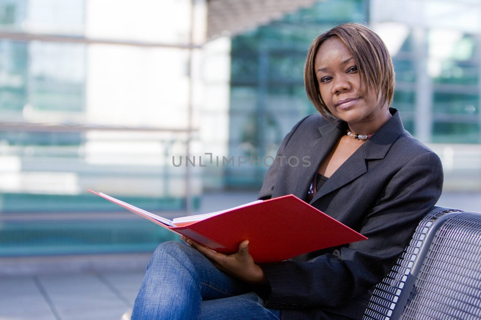 African american business woman reading documents in a folder in front of an office building