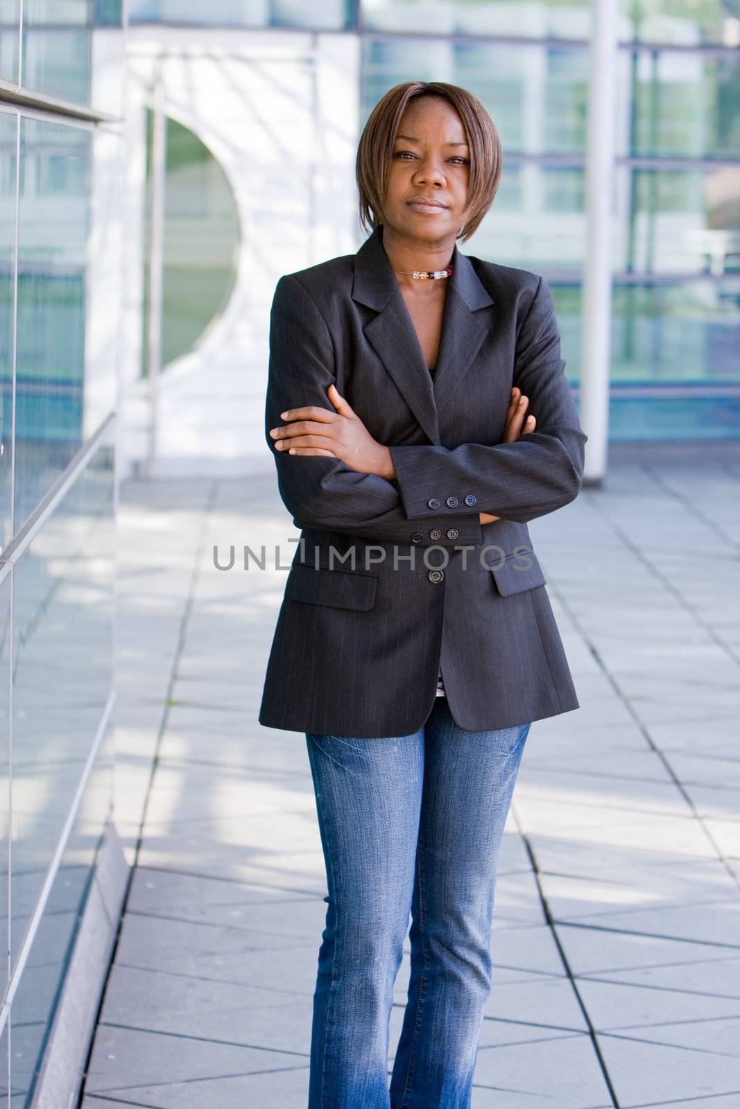 Black african american business woman posing in front of a modern office building with arms folded