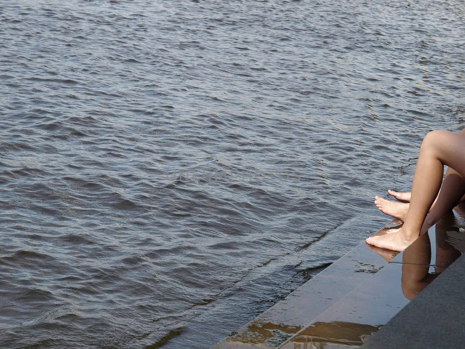 Girls legs bathing on the river or sea side seated on steps