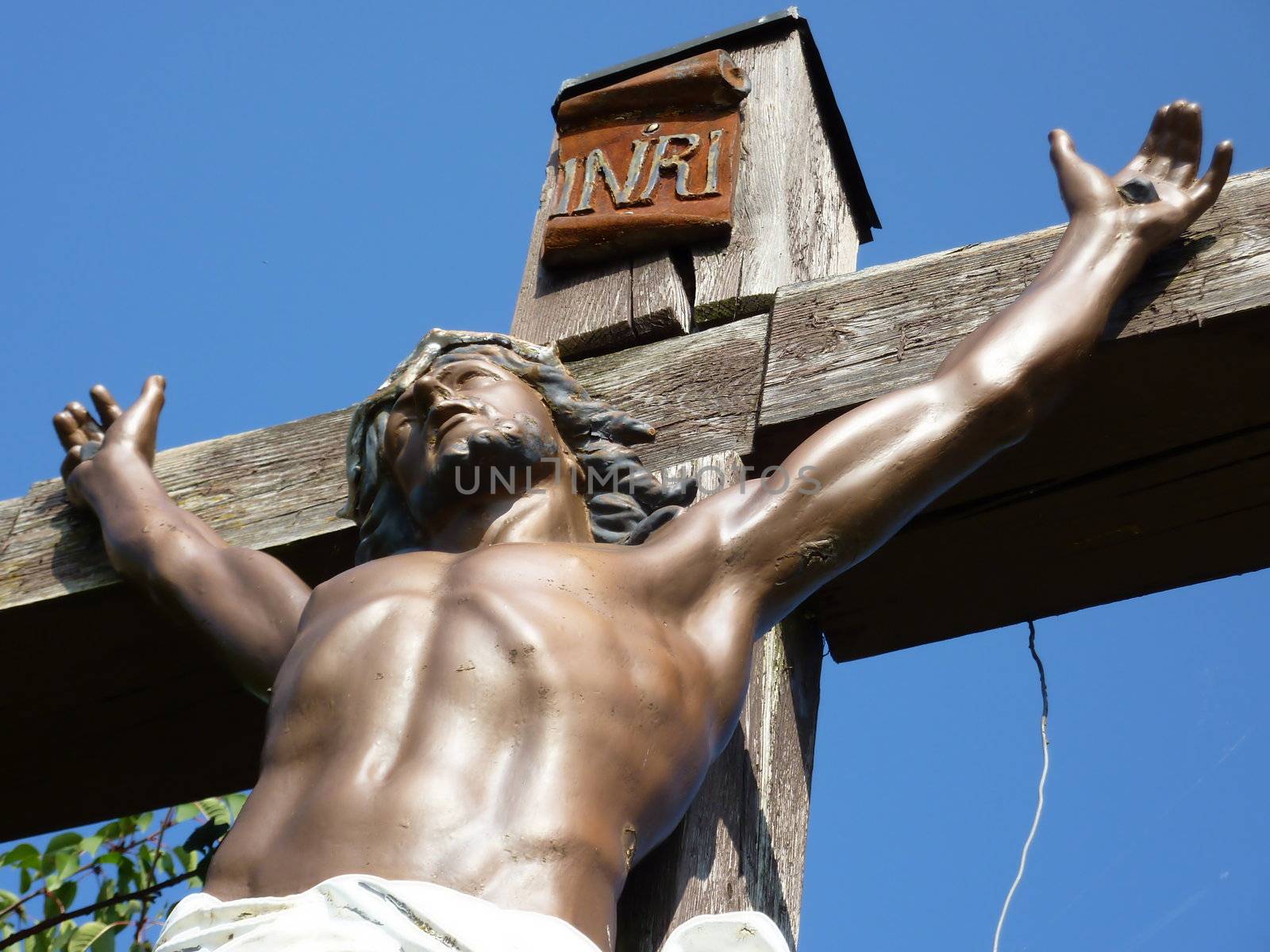 Jesus up body on a wood cross with blue sky