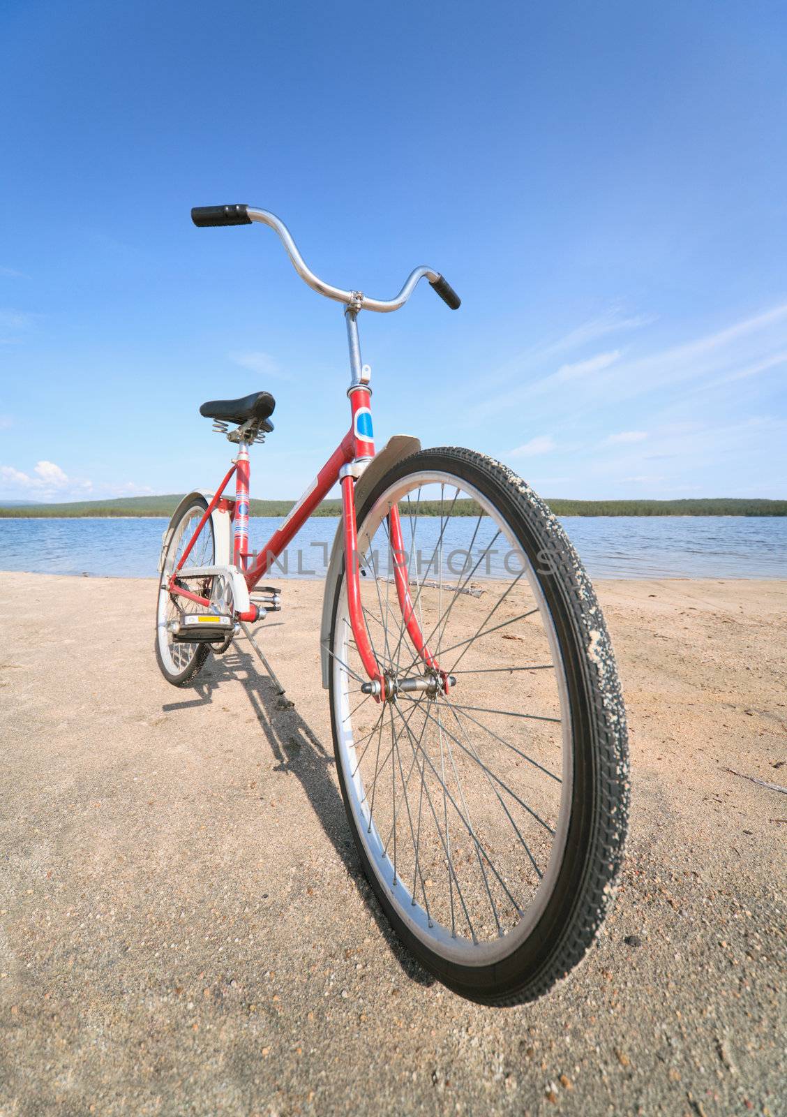 Old red bicycle photographed on a summer beach