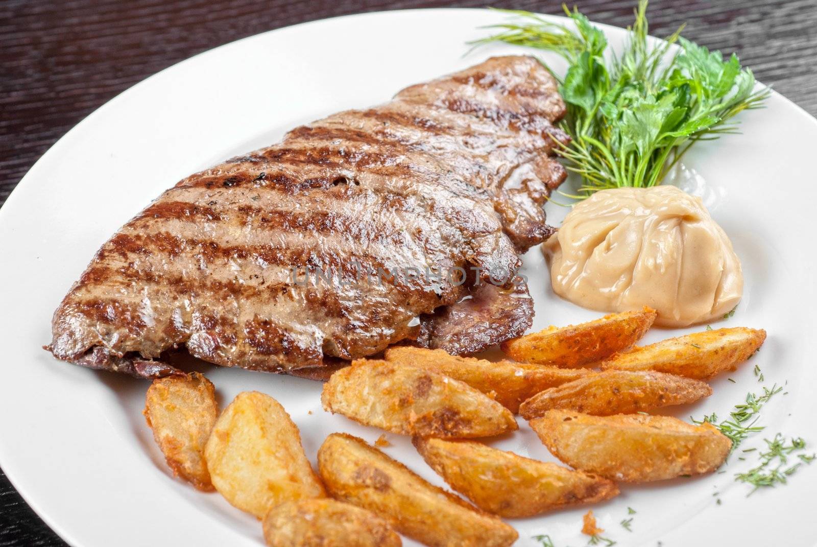 Juicy beef steak stuffed with beef tongue and cheese served with potatoes, greenery and sauce