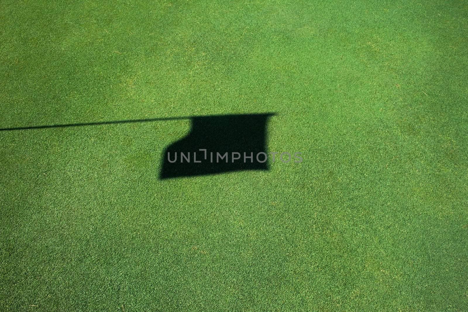 Shadow of flag on top of pin on a golf green