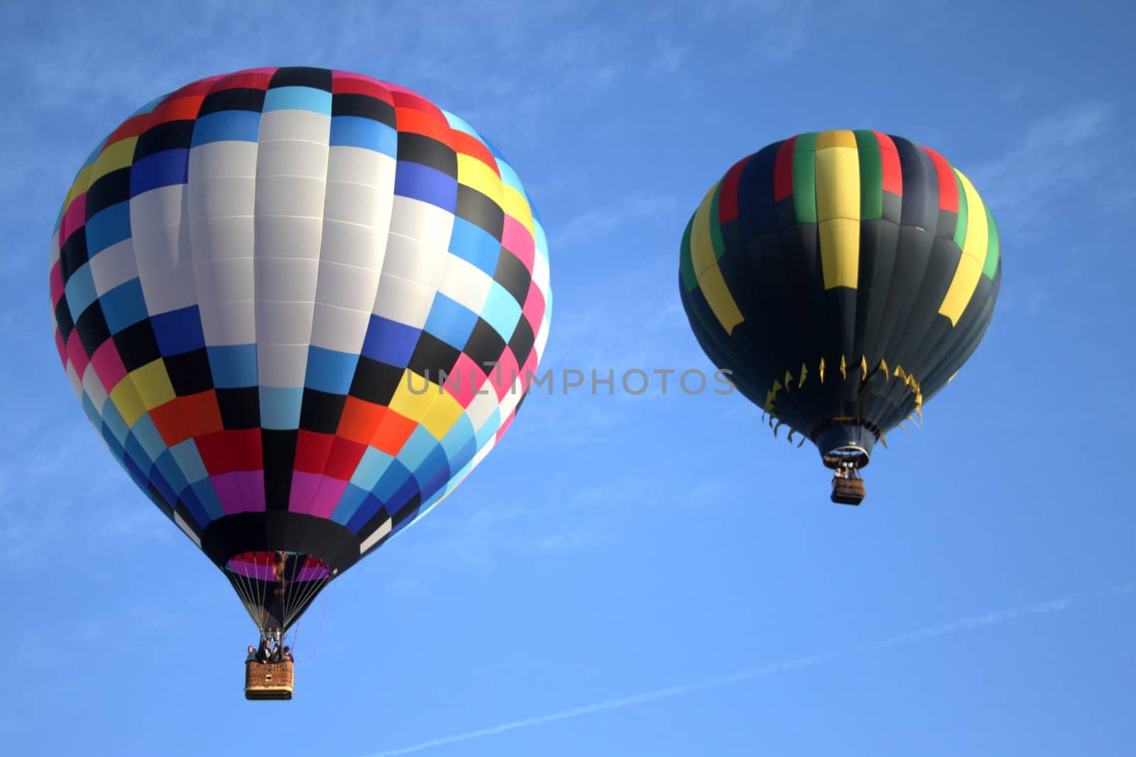 Pair of hot air balloons flying accross a blue sky